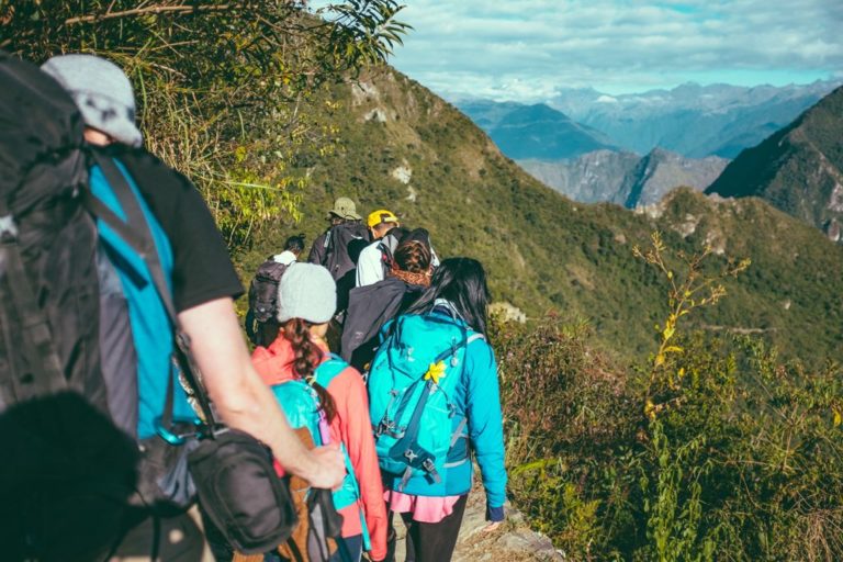 Group of hikers walking on trail in sunny weather in Aguas Calientes, Peru