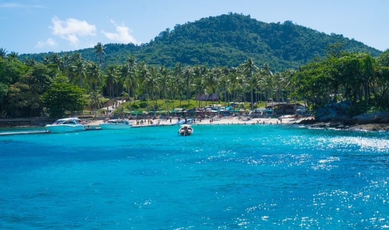 Speedboat cruising on clear turquoise tropical waters near Racha Yai Island under a bright sky