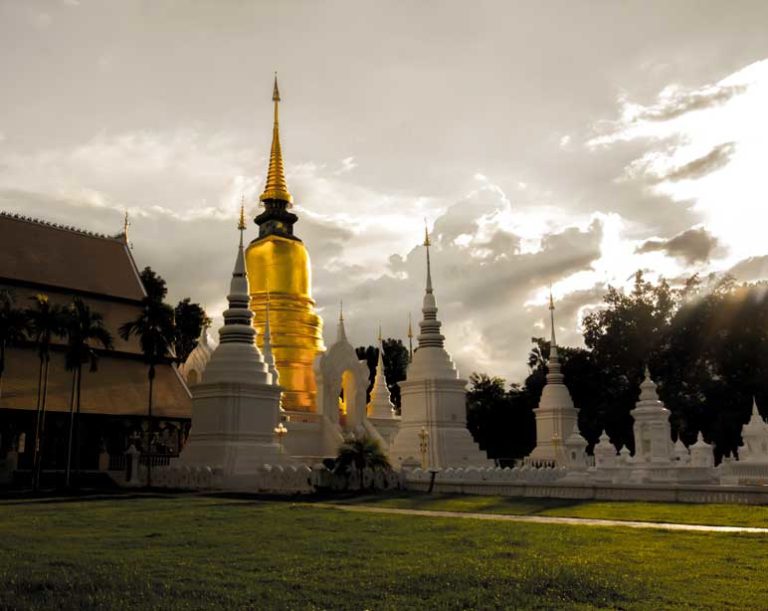 A visitor exploring a historic temple in Chiang Mai, surrounded by traditional architecture and lush greenery.
