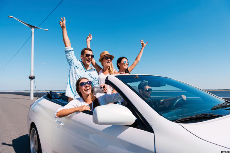 Car driving on a sunlit road during summer with family inside enjoying the trip