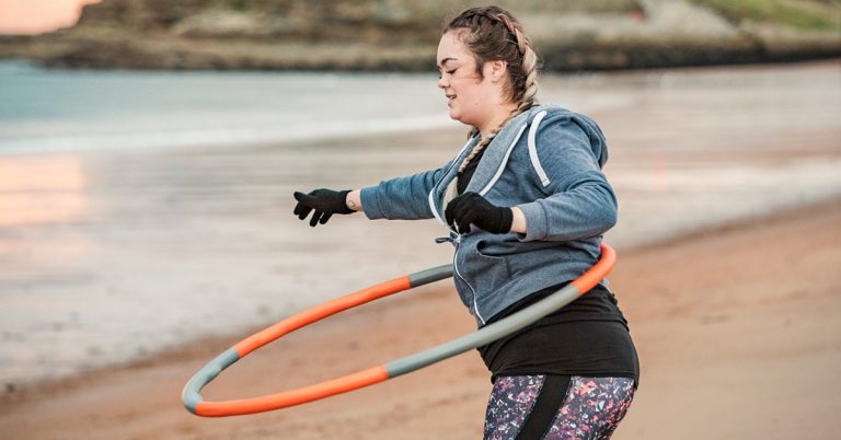 Person using a weighted hula hoop around their waist, demonstrating a low-impact fitness activity.