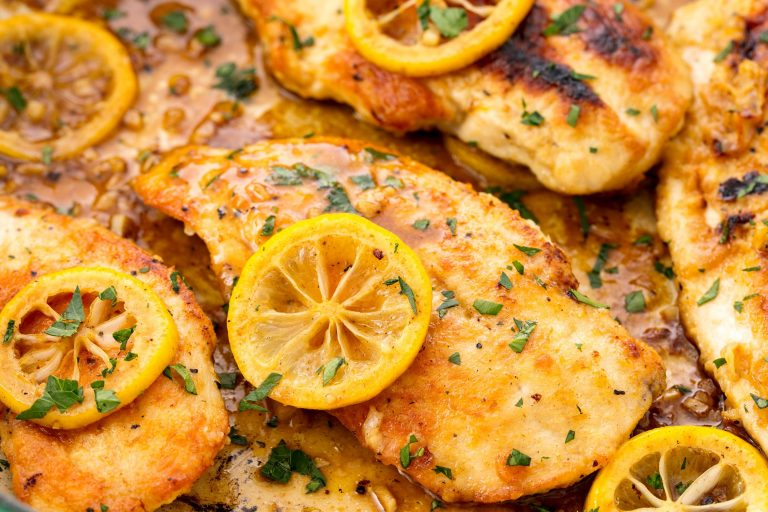 Golden seared skinless chicken breast seasoned with lemon pepper, garnished with lemon slices and herbs